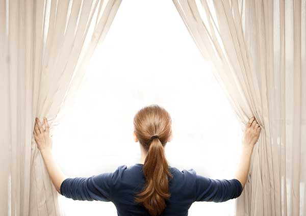 Woman opening the blinds for natural air