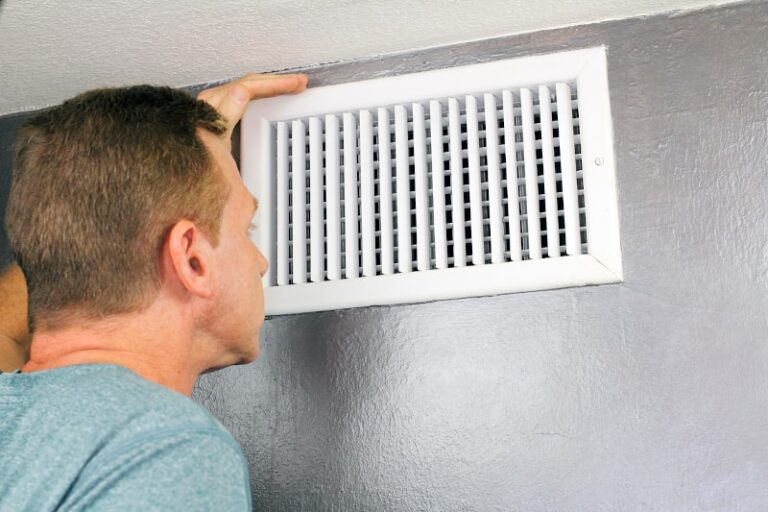 man checking air vent for AC odors